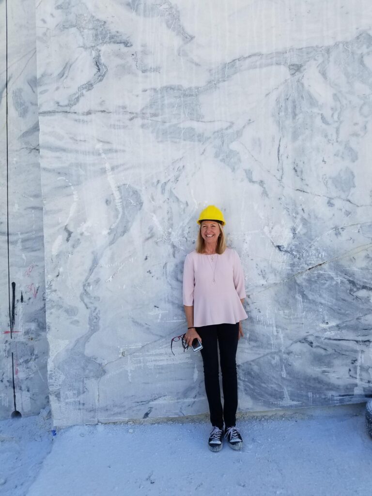 Designer Pam Sessons from Hedgewood Homes standing inside Georgia Marble quarry in Tate, Georgia with White Cherokee visible behind her.